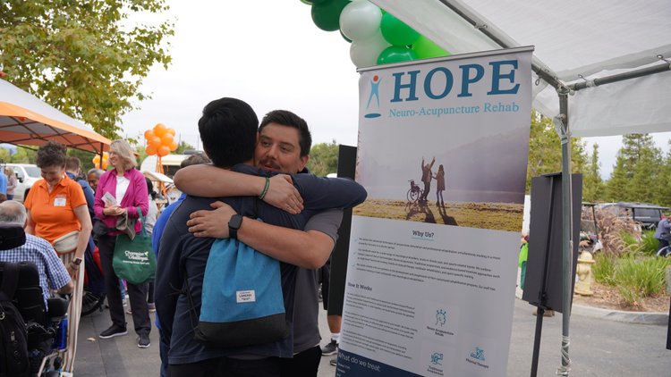 Two staff members embracing at HOPE Clinic community stroke awareness event