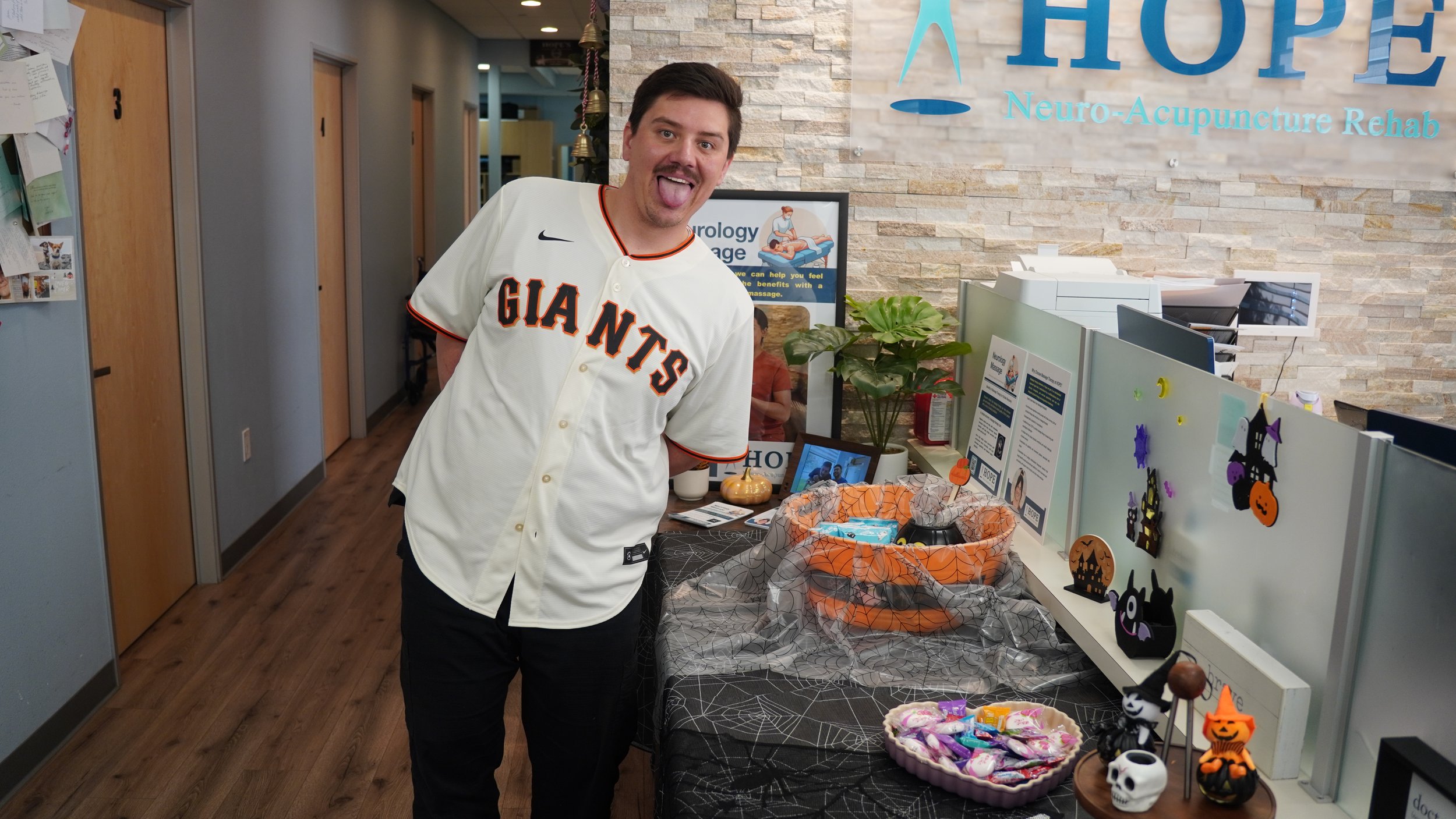 Staff member in Giants jersey at Halloween candy display at HOPE Clinic front desk
