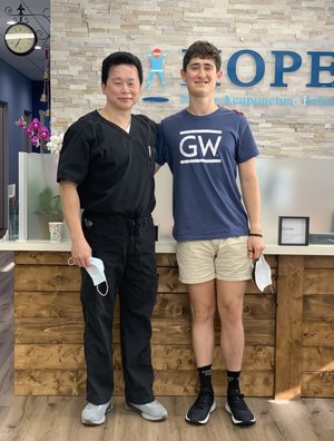 Dr. Lu and young patient posing together in HOPE Clinic lobby