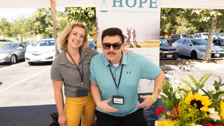 Two HOPE Clinic team members smiling at community outreach booth