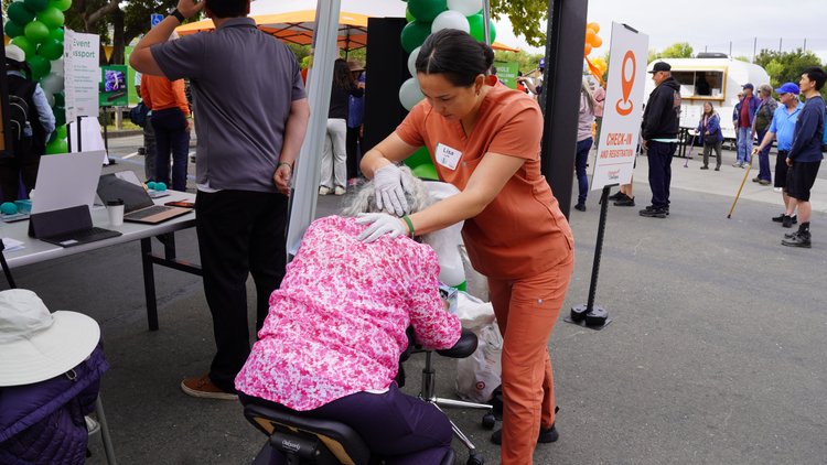 HOPE massage therapist providing chair massage to attendee at community health fair