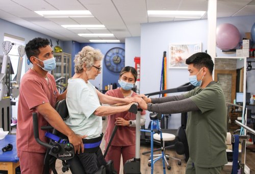 Therapy team assisting elderly patient with standing exercise on EasyStand device