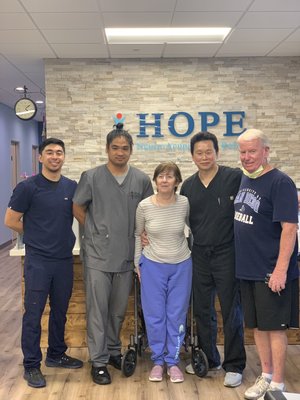 Clinic team with patient and spouse posing together in lobby