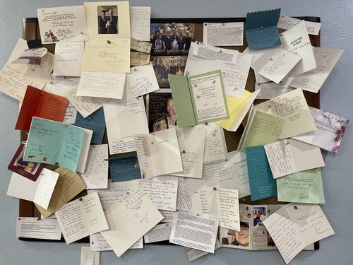 Bulletin board filled with handwritten thank-you cards and photos from grateful patients