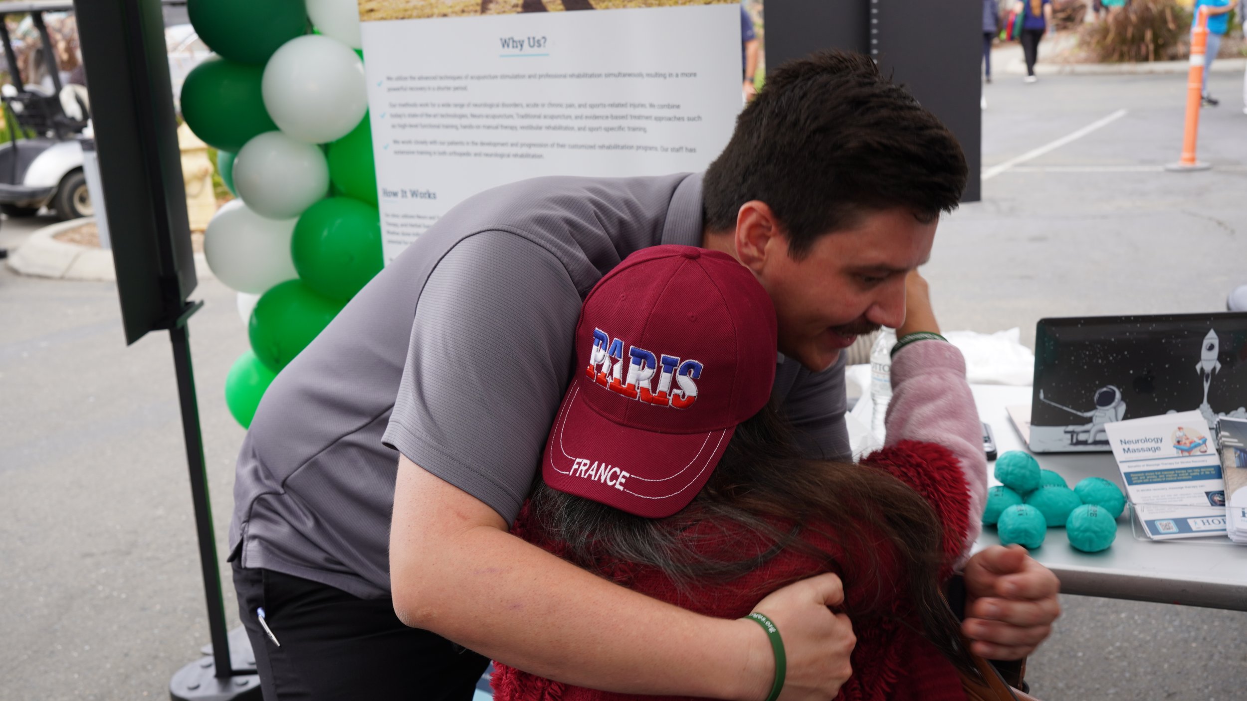 Staff member hugging visitor at HOPE Clinic community event booth